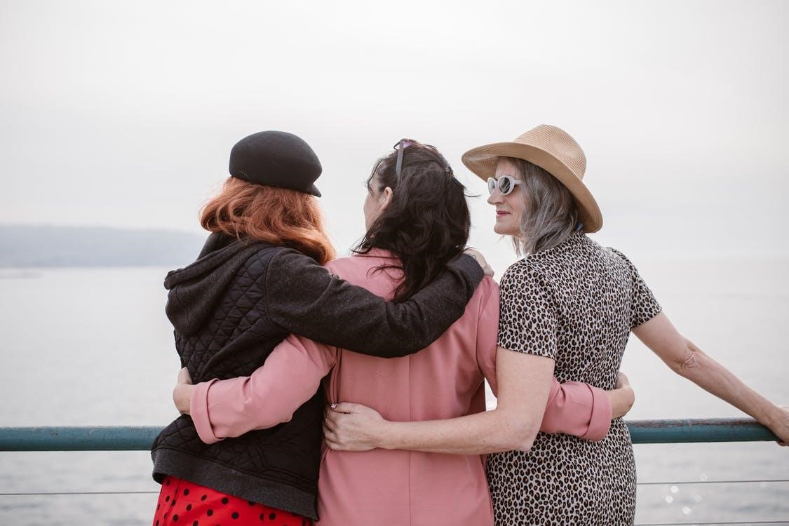 Backview of three girls holding each other while standing