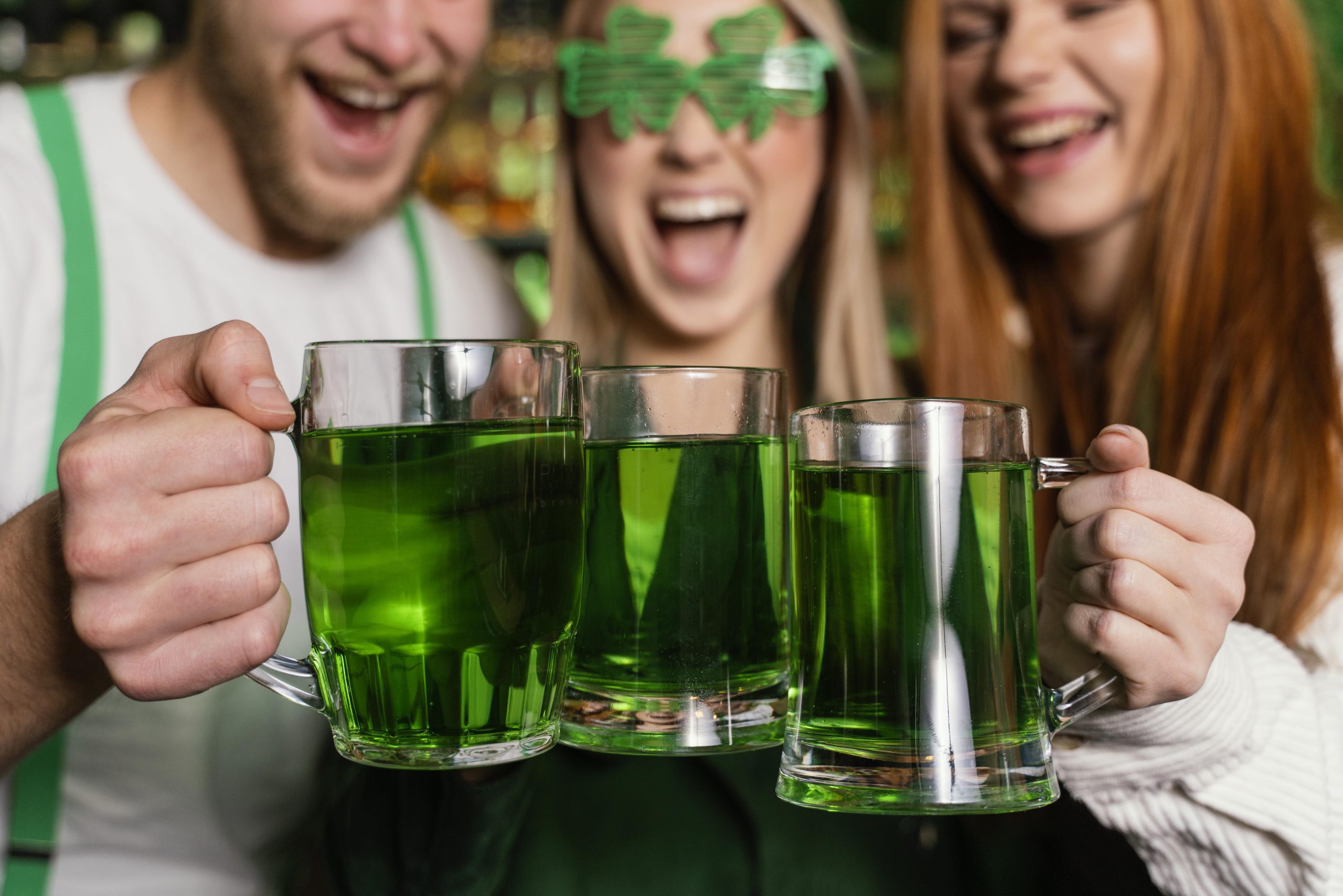 group of friends toasting with green beer saying st. patrick's day quotes and toasts