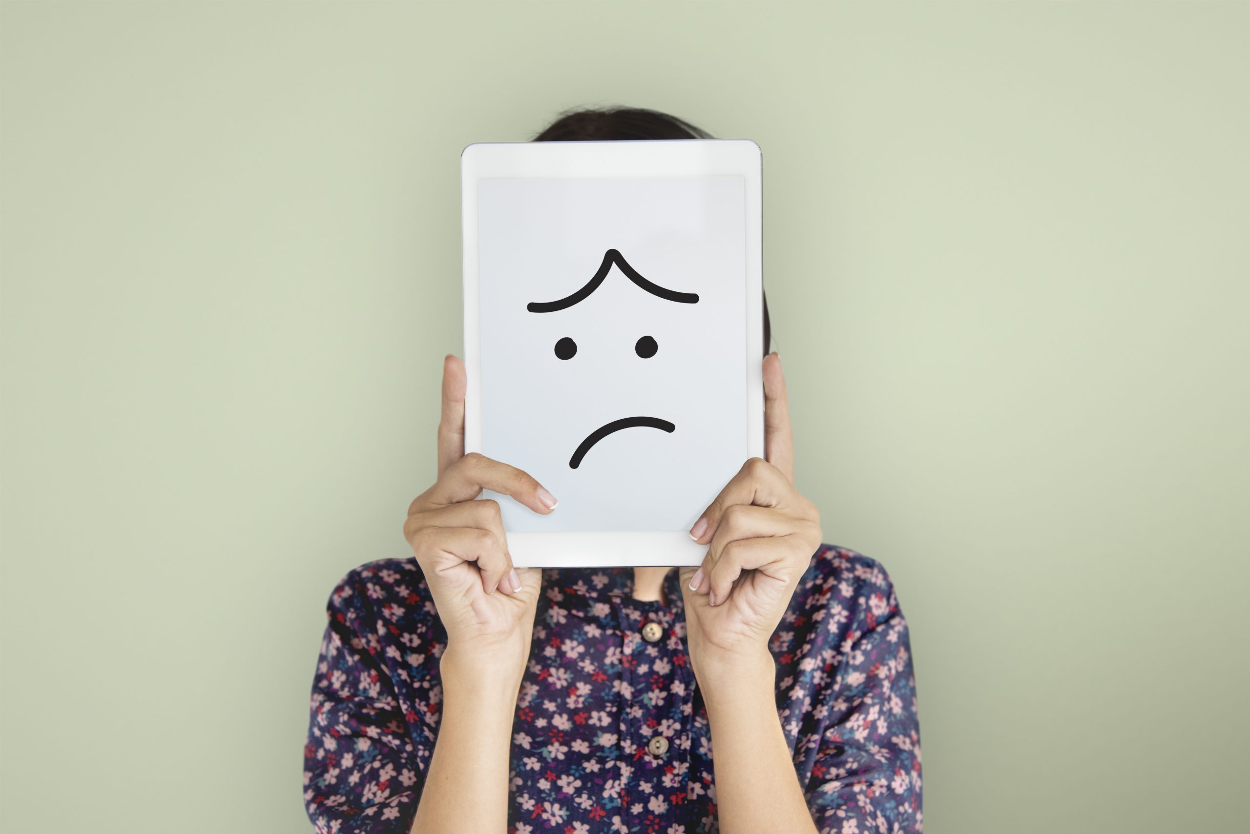 woman holding up sad face expression drawing