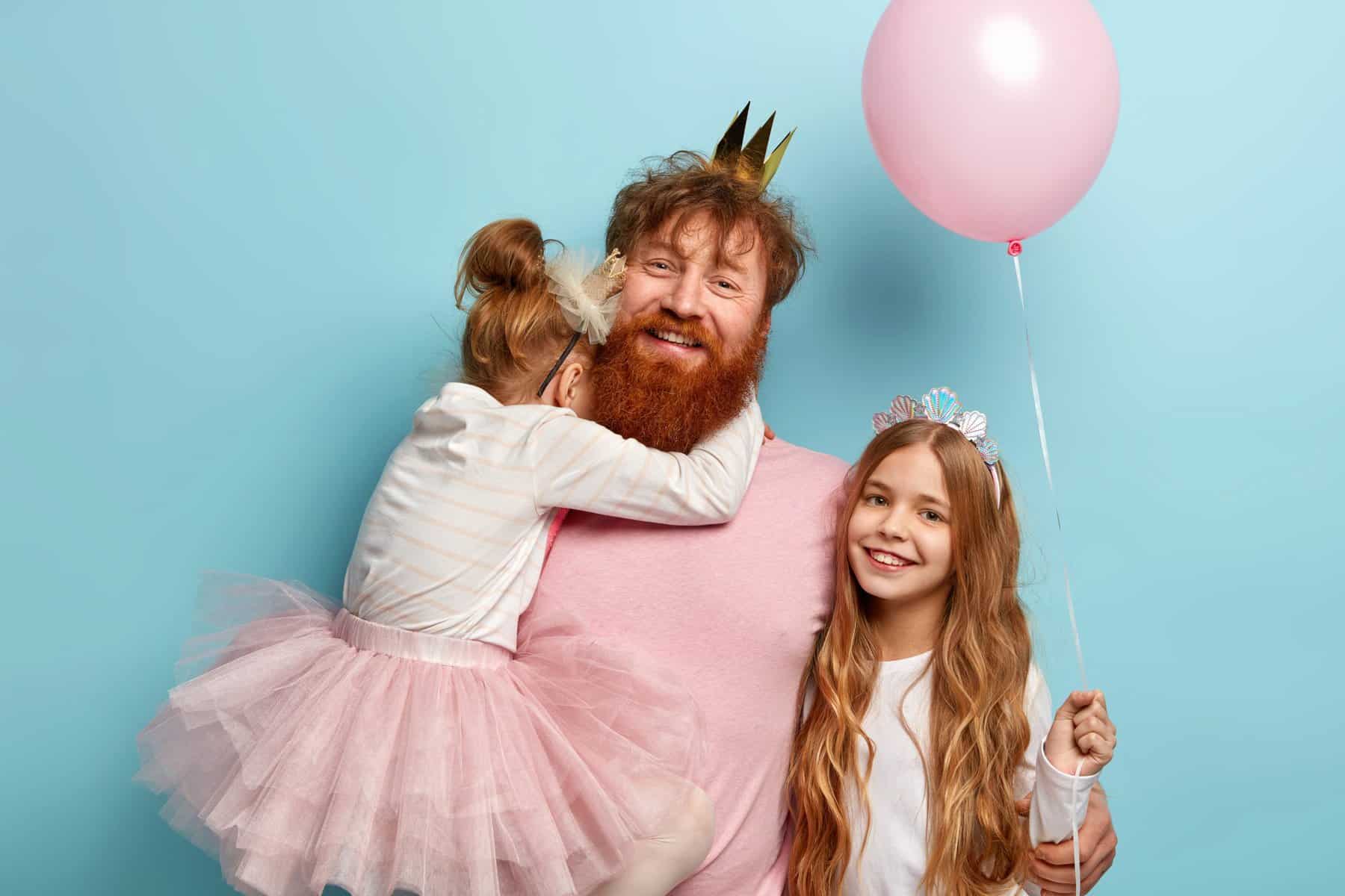 father wearing pink funny clothes with daughters