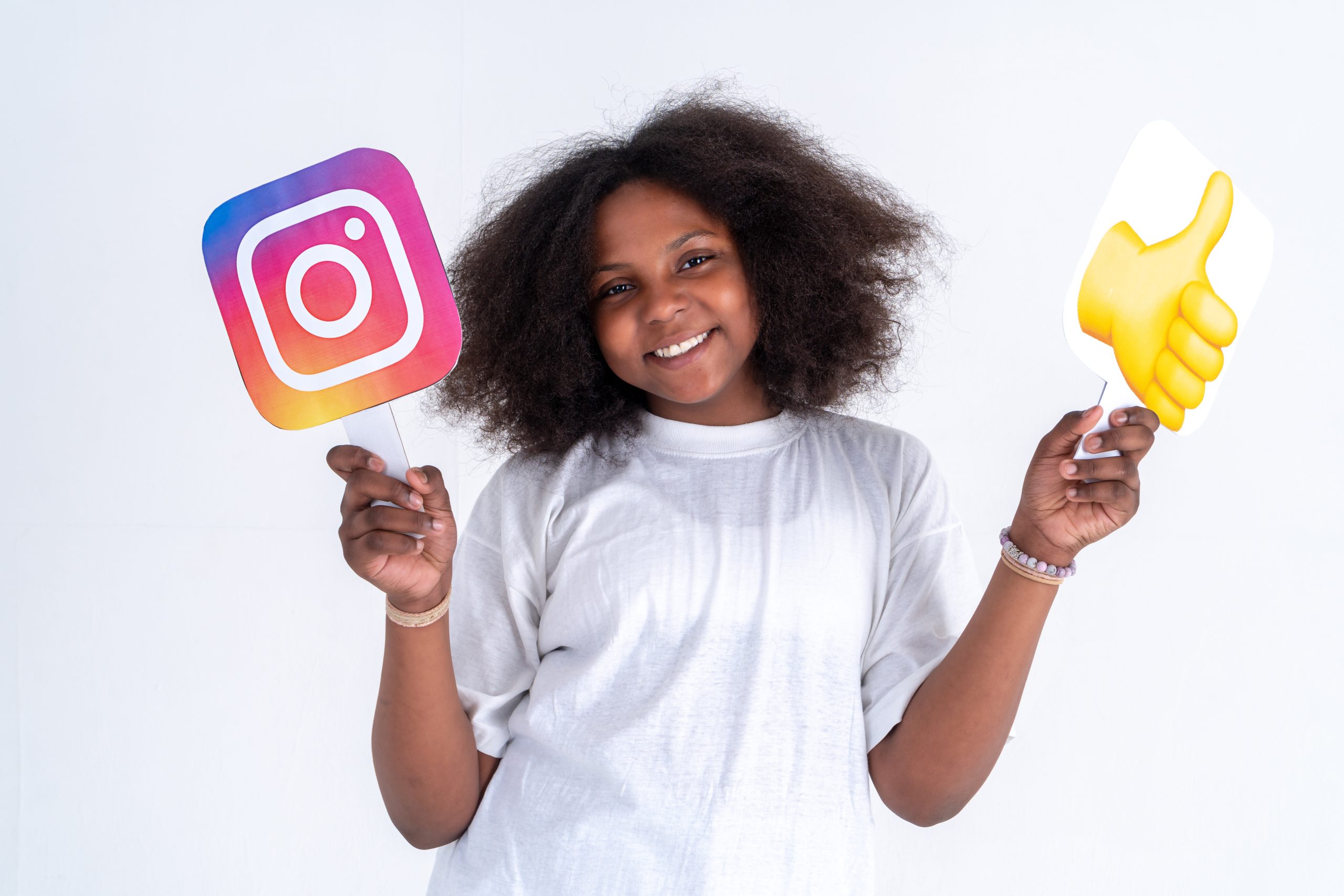 happy black girl with curly hair holding instagram logo and th